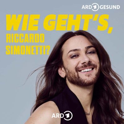 Nahaufnahme von Riccardo Simonetti mit langem Haar und Bart vor grauem Hintergrund, daneben gelber Text.